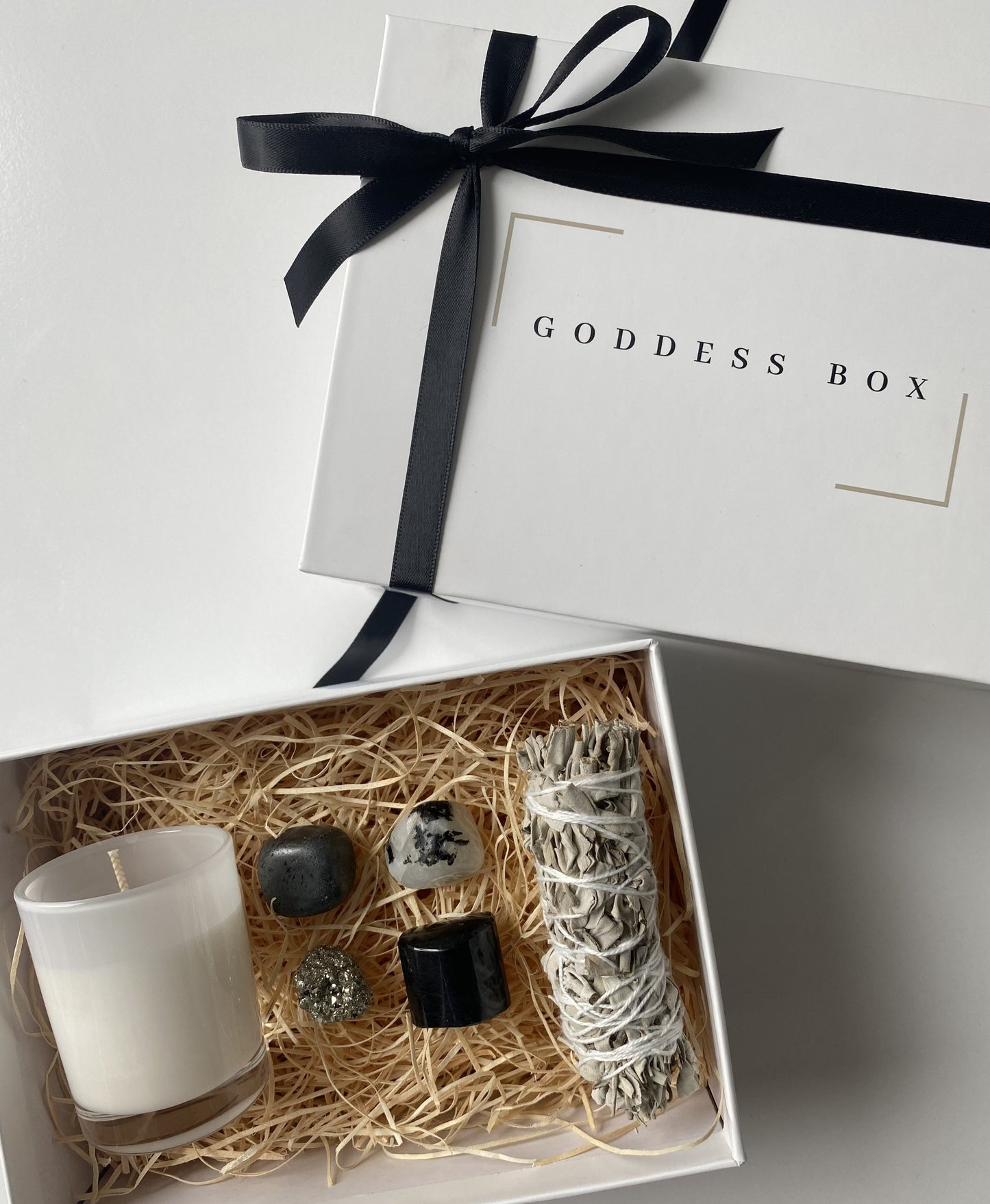 black and white crystal gift boxes. Includes hematite, moonstone, pyrite, black tourmaline and sage stick. Each box also comes with a gardenia scented candle